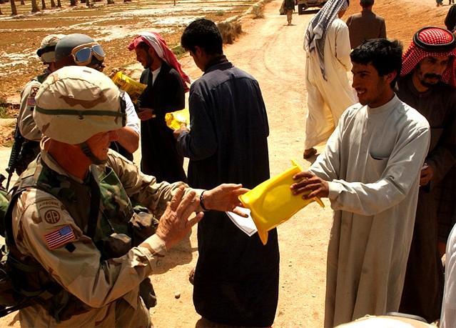 Staff Sgt. Joseph Cole, headquarters commandant, HHC 82nd Airborne Division, hands a humantarian ration to a young Iraqi man near As Samawan. (U.S. Army photo by Staff Sgt. Eric Foltz, 49th PAD)