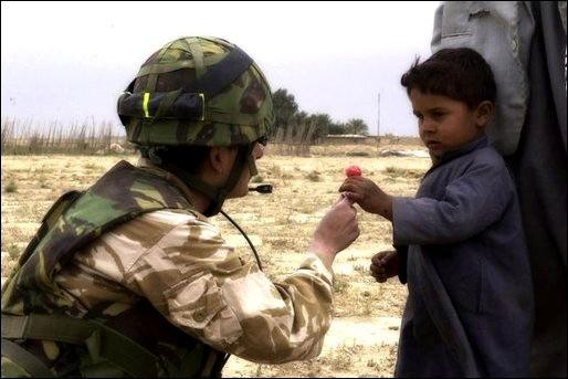 An RAF Regiment gunner shares sweets with an Iraqi child