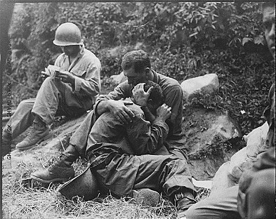 A grief stricken American infantryman whose buddy has been killed in action is comforted by another soldier.  In the background a corpsman methodically fills out casualty tags, Haktong-ni area, Korea.  August 28, 1950.  Sfc. Al Chang. (Army) Photo Source - National Archives