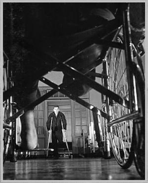 Wounded soldiers use wheelchairs and crutches until they learn how to walk with a synthetic limb. Private First Class, Charles Woody, injured near Taegu, walks on crutches. Walter Reed Military Hospital. Washington DC December 8, 1950 Contributors:  Knudsen, Photographer Trehearne. Tech Sergeant, Photographer